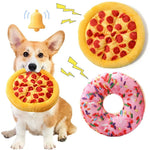 Dog holding a plush pizza toy with additional pizza and donut toys in the background.