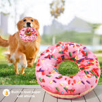 Dog playing with a pink donut-shaped toy outdoors