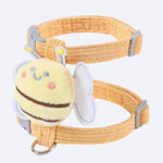 Yellow dog collar with a bee-shaped plush toy attachment on a white background