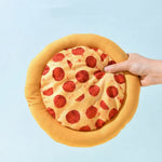 Yellow pizza-shaped plush dog toy held in a hand